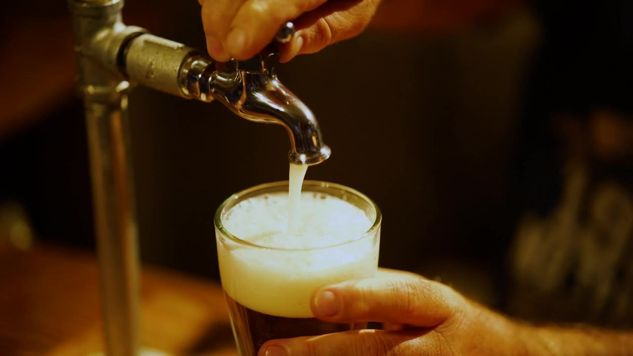 Une main tient un verre sous le robinet de la tireuse.